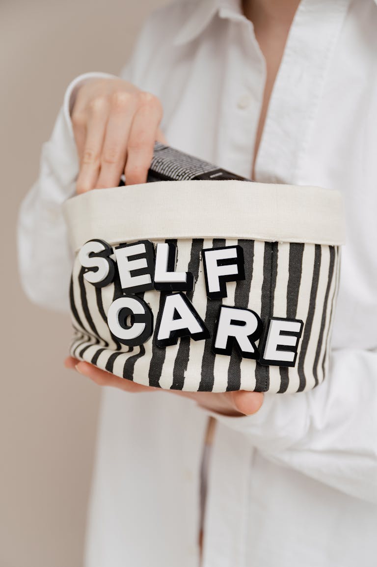 A person holding a striped bag with 'SELF CARE' letters promoting wellness and relaxation.
